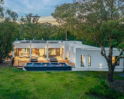 Architect-designed home with a swimming pool, expansive entertaining deck, floor-to-ceiling glazing and private landscaped grounds surrounded by native bushland.