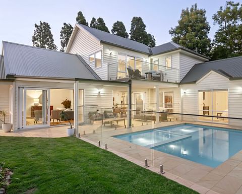 Curved glass-walled living area opening onto a stone terrace