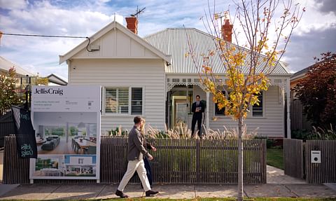 A family walking past a weatherboard Melbourne home in autumn