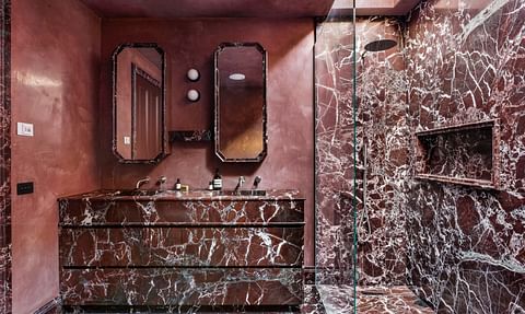A richly detailed bathroom featuring red marble and dark timber joinery